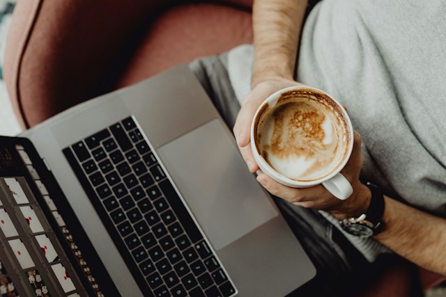 A person working on a laptop with a cup of coffee nearby.