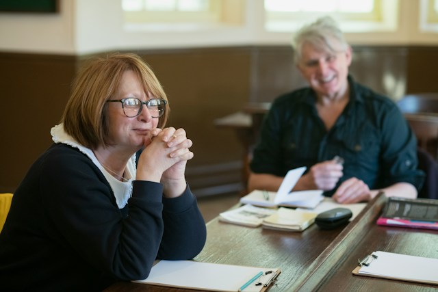 Two colleagues reviewing notes and papers at a table.