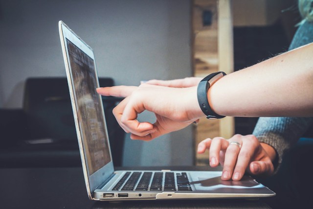 Two colleagues looking at a laptop together.